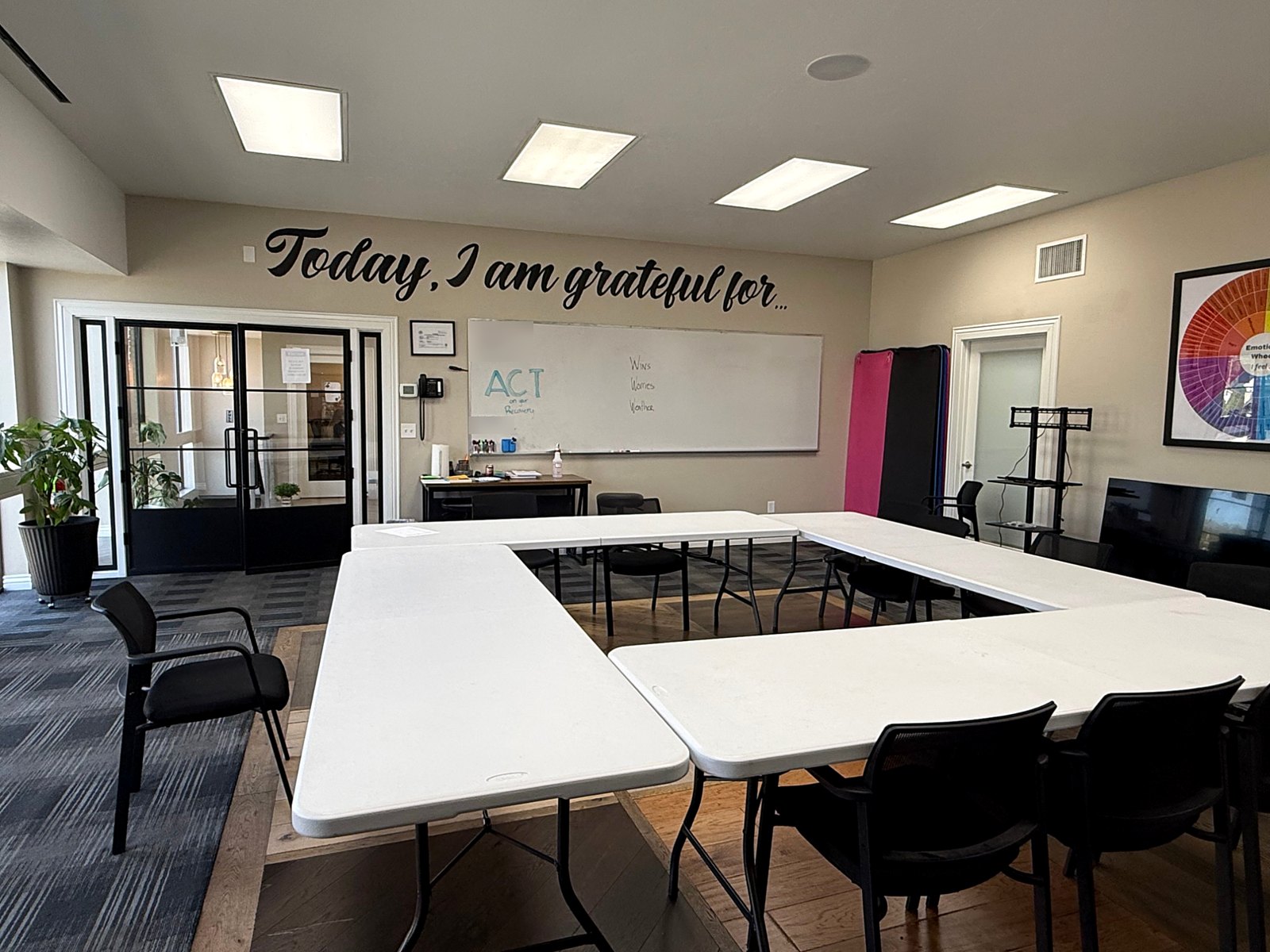 The Phoenix Rising treatment group room, set up for a session under the wall message Today, I am grateful for